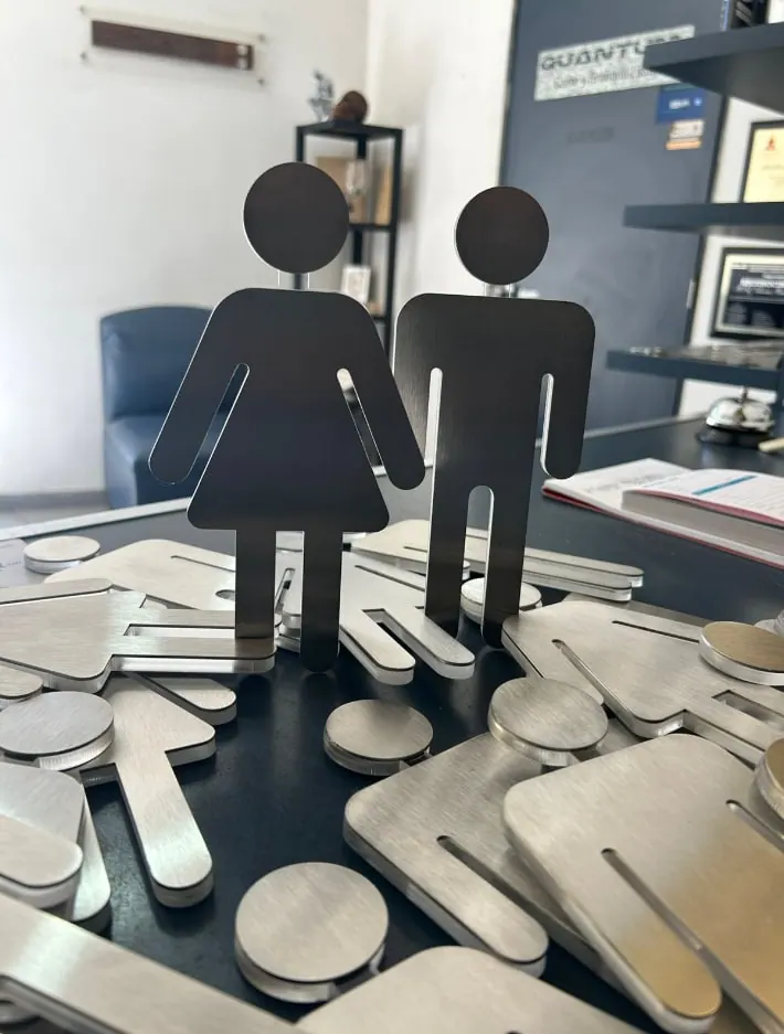 Figuras de mujer y hombre cortadas en metal, entre piezas y separadores de la misma serie