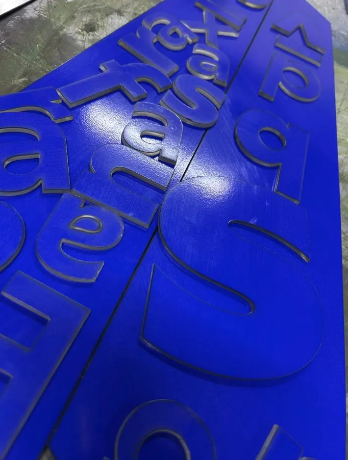 Letras de acrílico azul recién cortadas sobre la lámina