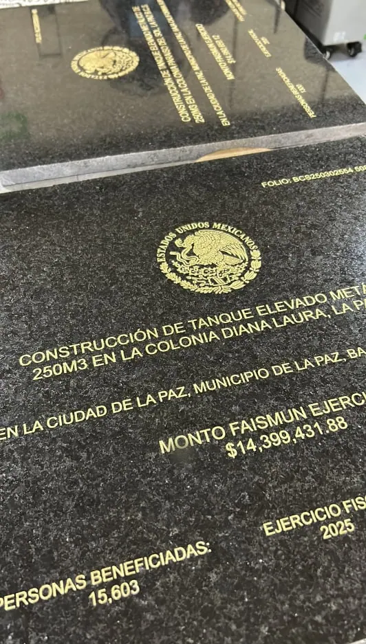 Placa de granito negro con texto de obra pública grabado en dorado
