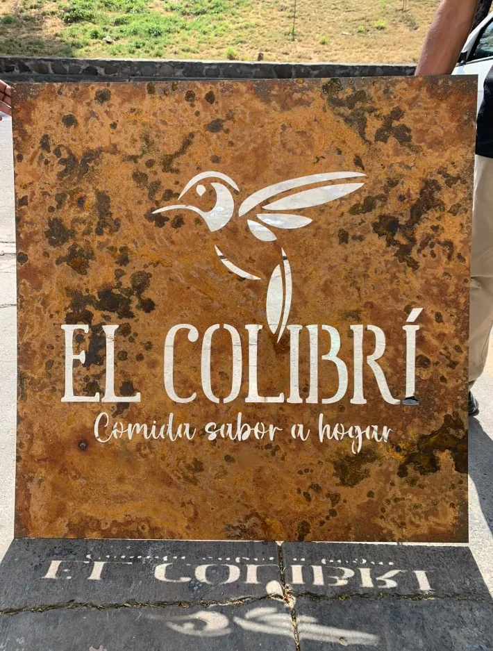 Letrero de acero con pátina de óxido, un colibrí y texto calados