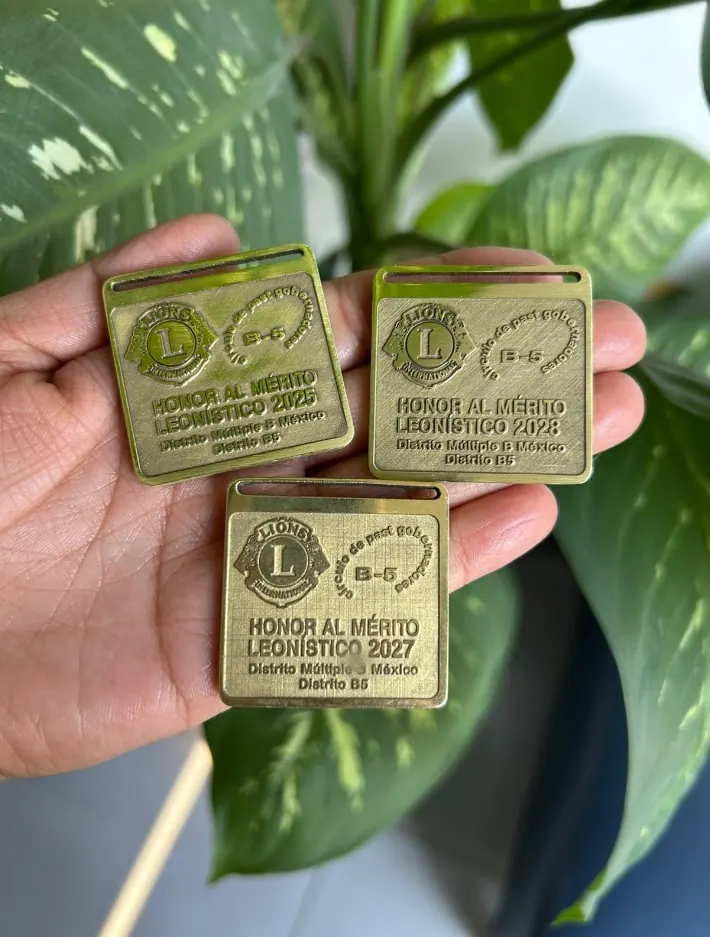 Medallas doradas de reconocimiento con texto grabado