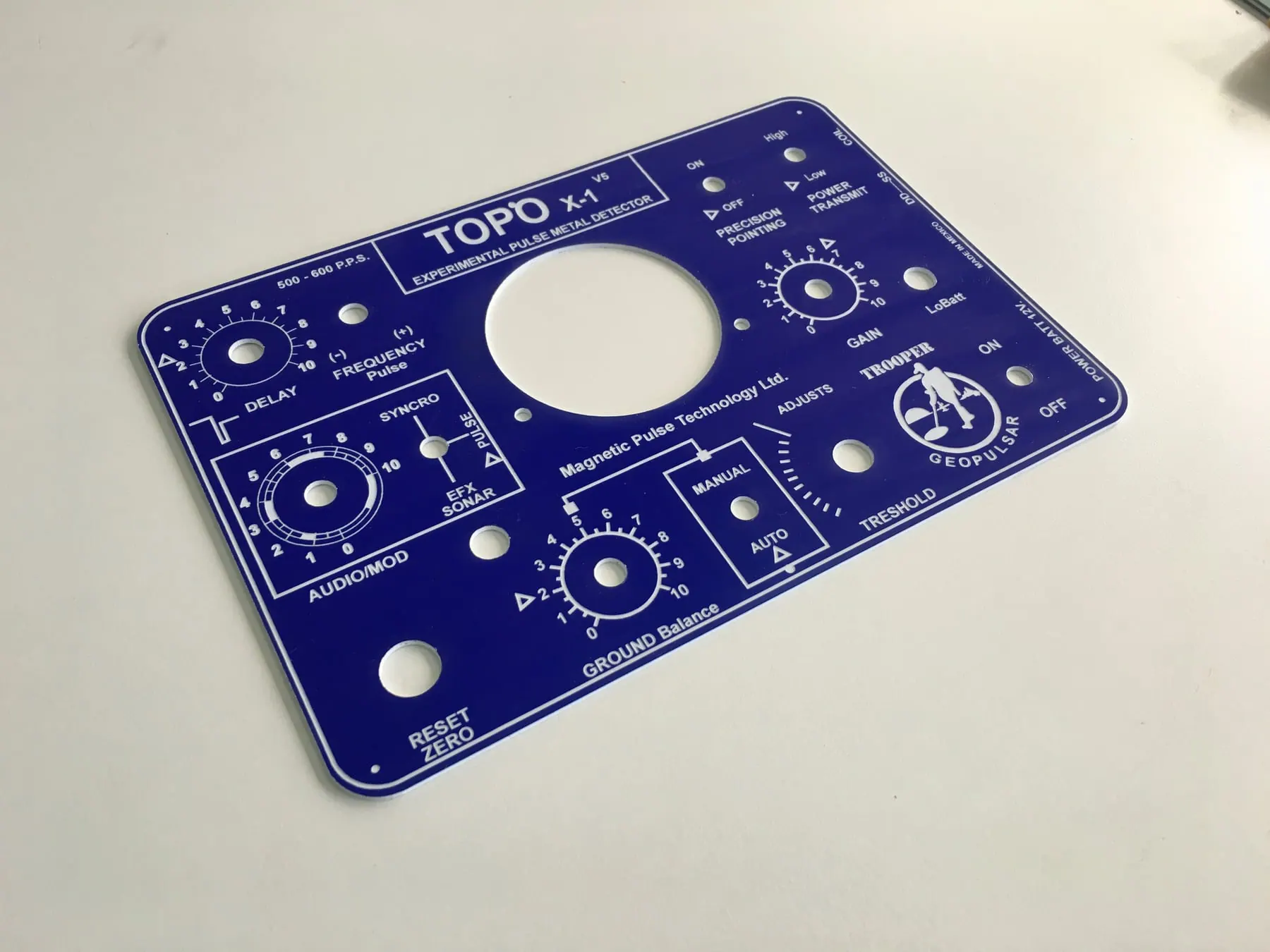 Panel de control de aluminio anodizado azul con perforaciones y rótulos grabados en blanco