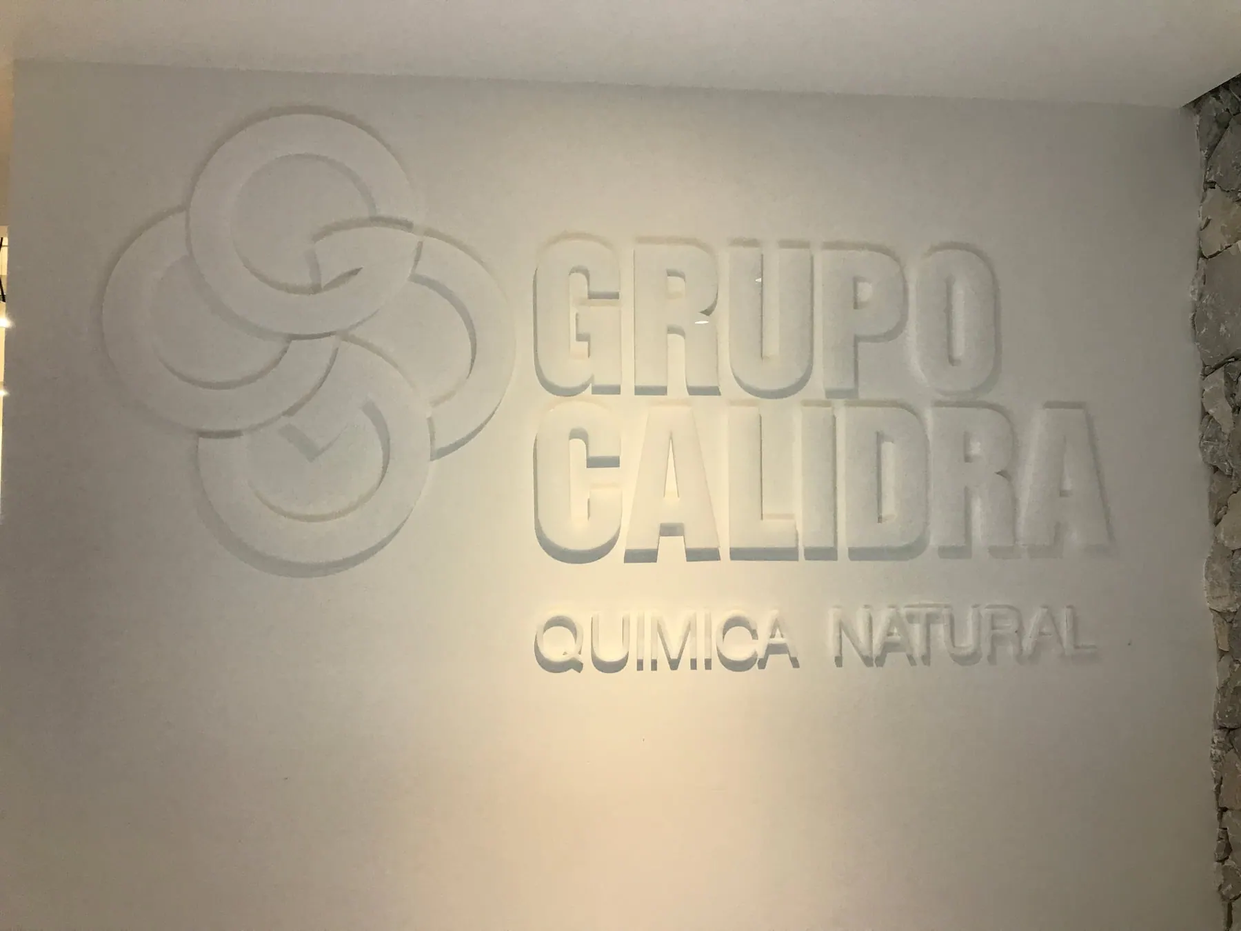 Logotipo corporativo en relieve sobre un muro blanco