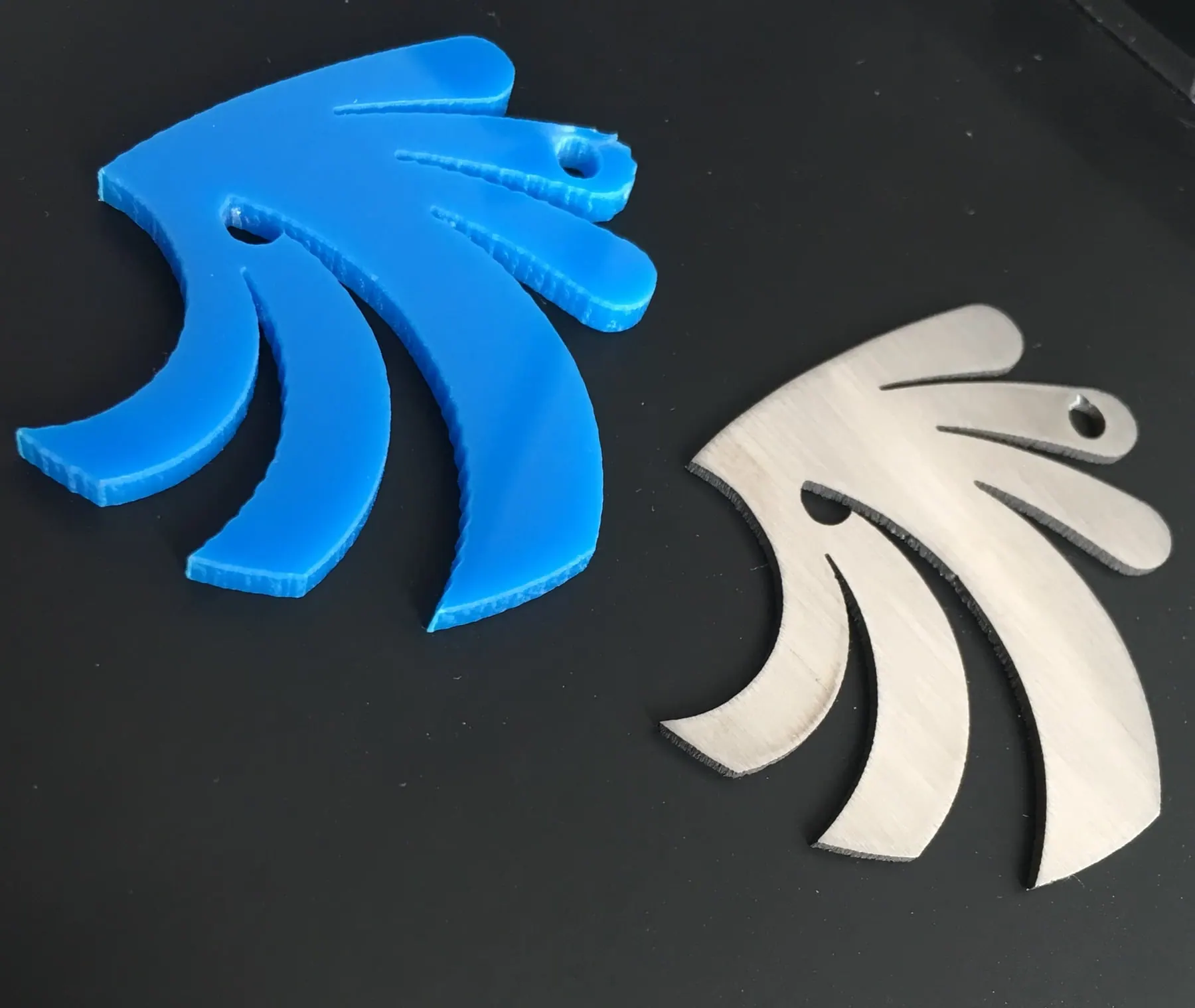 Piezas con forma de ala cortadas en acrílico azul y en metal